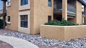 A two-story building with a beige exterior, multiple windows, and a balcony. - Foothills 2-bedroom condo in welcoming Tucson with AC and fitness room (Tucson)
