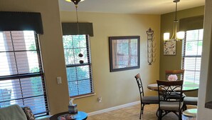 A dining area with a round table and chairs, a ceiling fan, and a window with blinds. - Foothills 2-bedroom condo in welcoming Tucson with AC and fitness room (Tucson)
