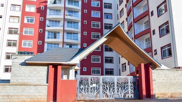 A multi-story residential building with a red and white facade, balconies, and a gated entrance. - The Greenzone Apartments Thindigua (Kiambu)