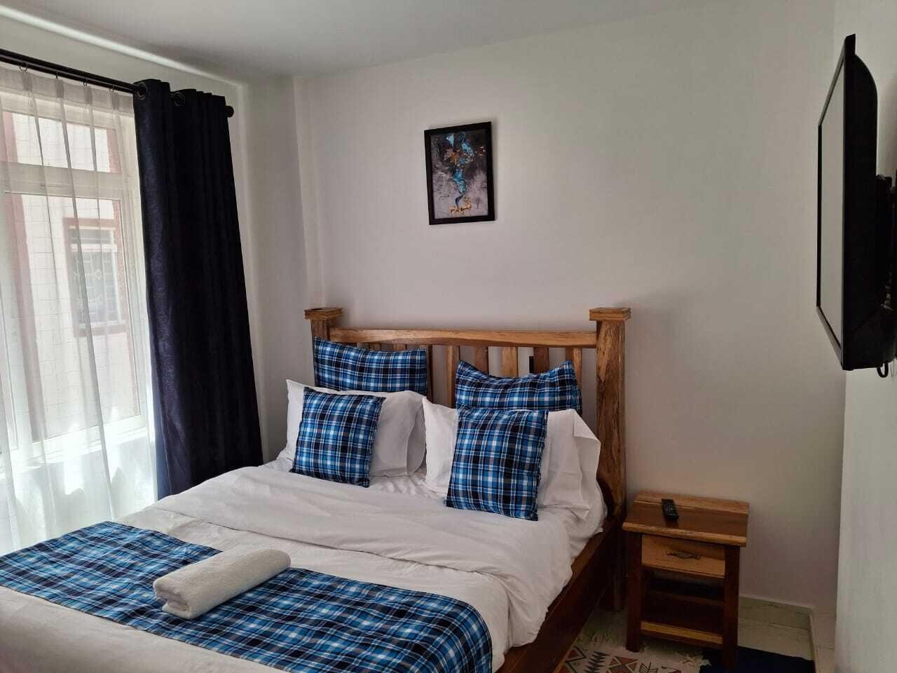 A neatly made bed with blue and white bedding, a wooden headboard, and a small bedside table with a lamp.