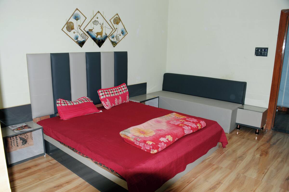 A bedroom with a bed, nightstands, a dresser, and a wall-mounted shelf with decorative items.