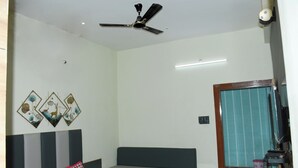 Una camera da letto con un letto, un ventilatore a soffitto, una TV a parete e una porta con tenda a righe.