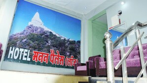 Un interno di hotel con un grande poster raffigurante una montagna e un tempio, sedute viola e una scala.