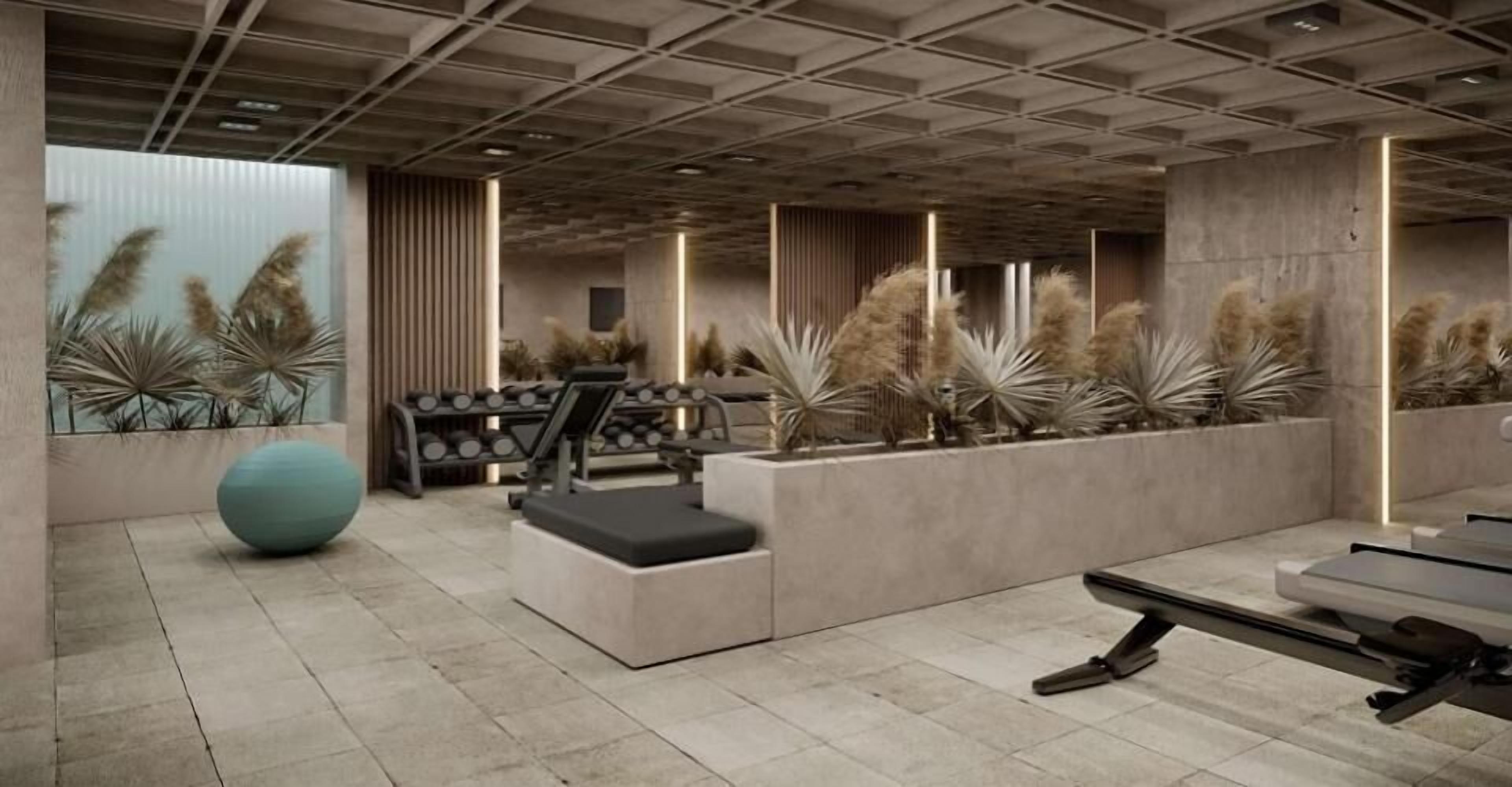 Een moderne sportschool met fitnessapparatuur, een grote fitnessbal en decoratieve planten.