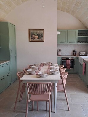 A dining area with a table set for six, surrounded by chairs, and a kitchen with green cabinets and a tiled backsplash. - Lovely 4 bed 3 bathroom country house & pool Prime location near Ceglie & Ostuni (Ceglie Messapica)