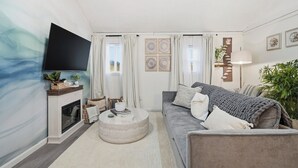 Un salon avec une cheminée, un canapé, une table basse et un téléviseur fixé au mur.