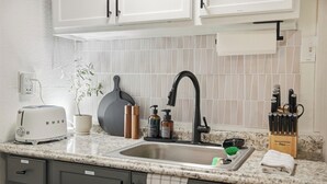 Une cuisine équipée d’un évier, d’un grille-pain, d’un bloc à couteaux et d’une plante en pot.