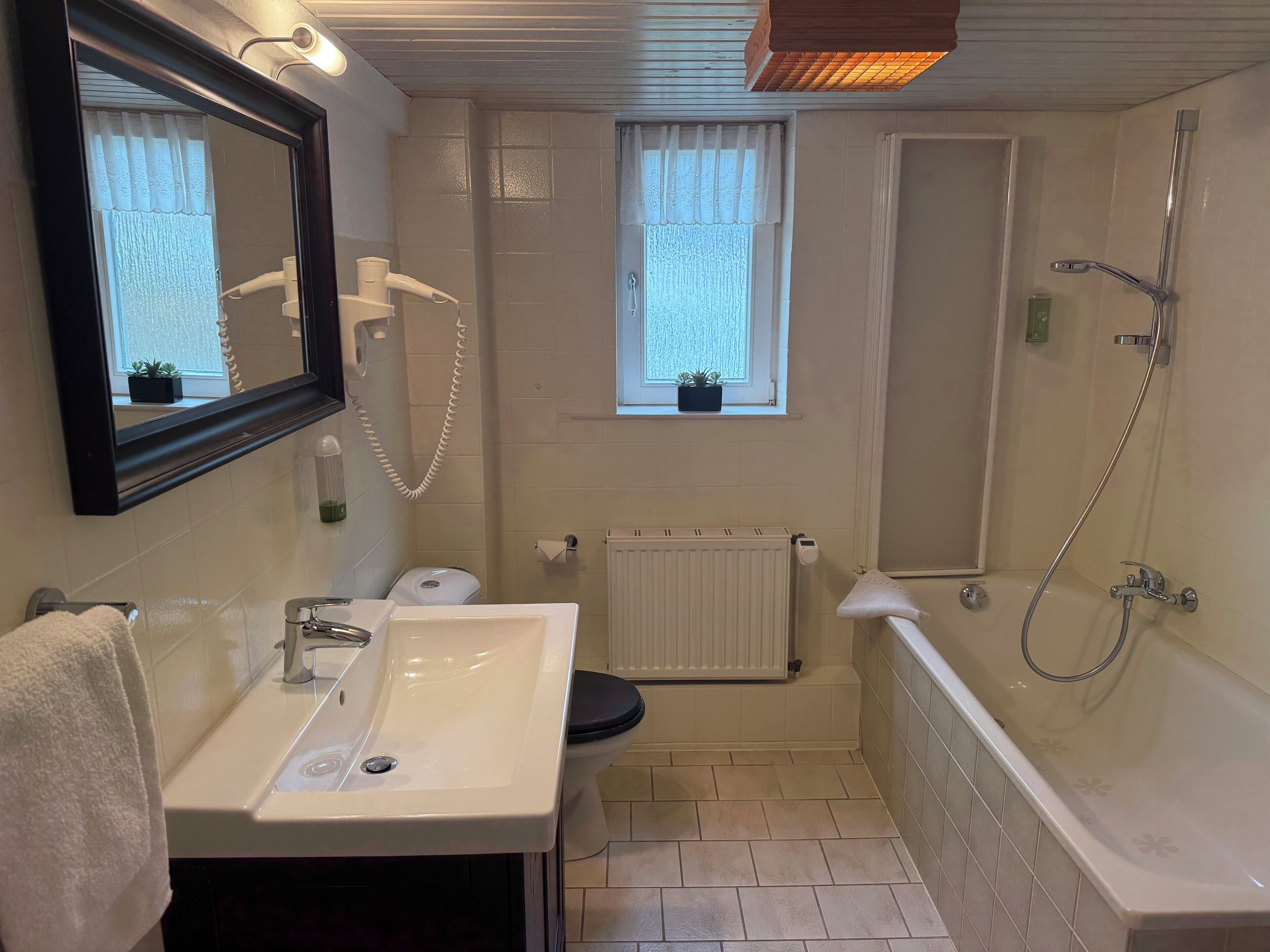 Et badeværelse med vask, toilet og badekar.