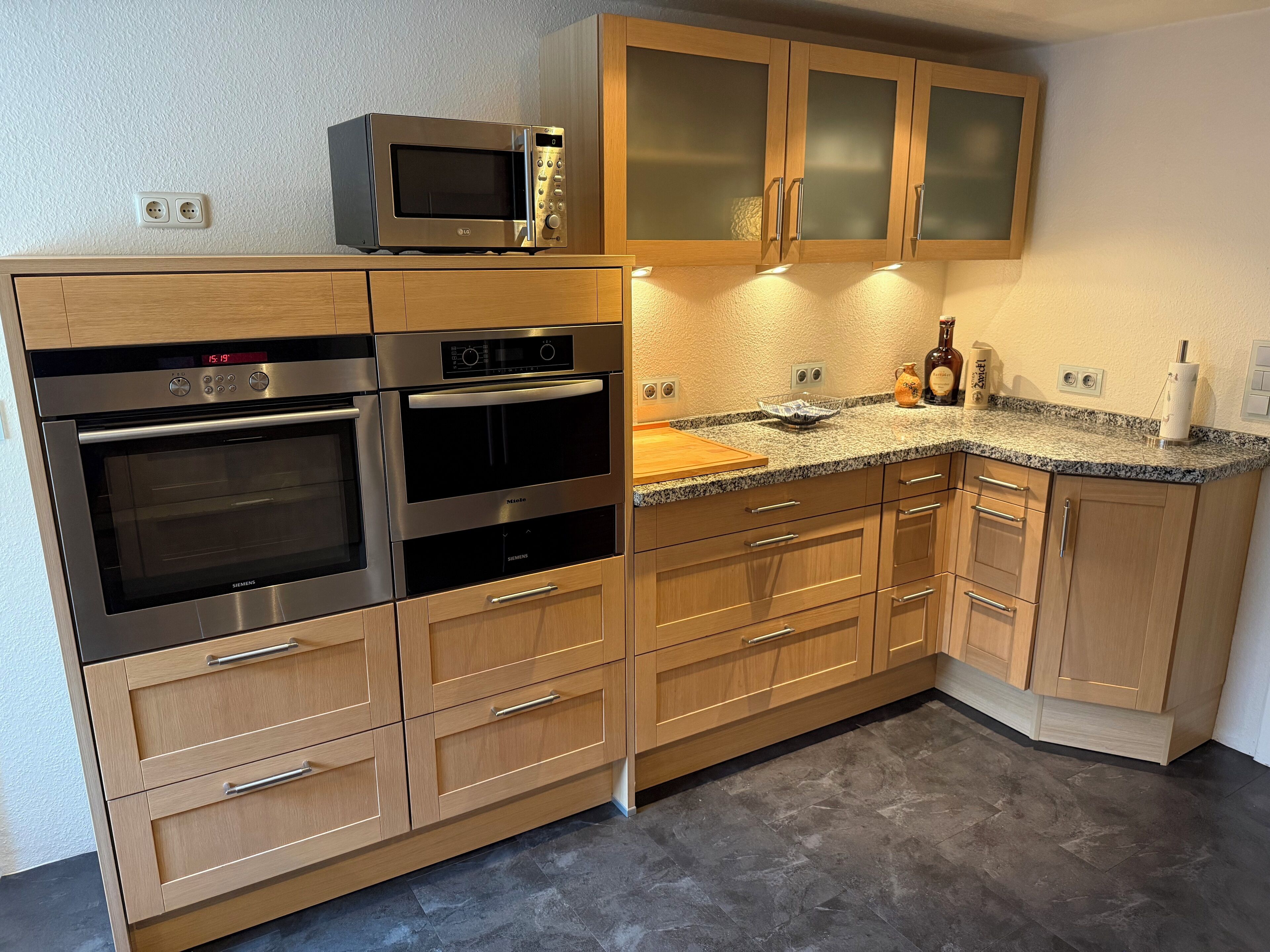 Una cocina moderna con hornos integrados, microondas y armarios de madera.