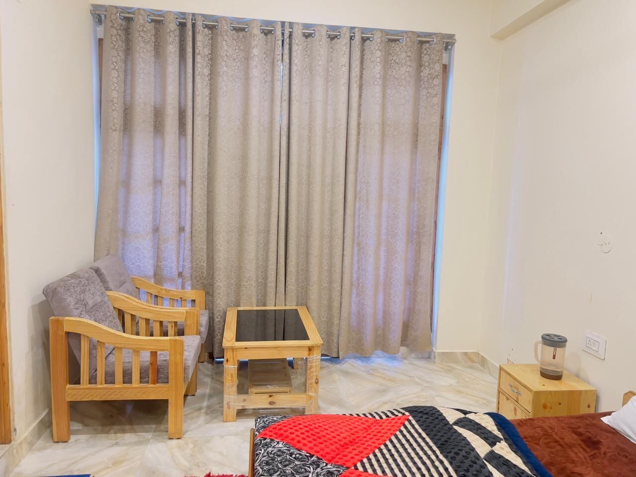 A small, cozy room with a wooden sofa, a small wooden table, and a red and black patterned rug.