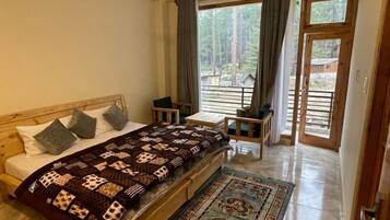 Un dormitorio con cama, escritorio, silla, ventilador de techo y vistas al exterior.