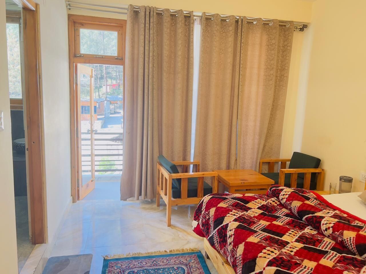 A bedroom with a bed, a wooden chair, a small table, and a view of the outside.