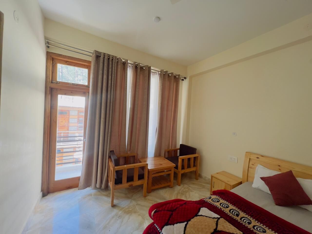 Un dormitorio con una cama, una mesa de madera y dos sillas.