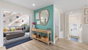 A modern living room with a teal accent wall, a wooden console table, and a built-in fireplace. - Enchanting Ocean View Townhome | Walk to Beach, Dining & More (Encinitas)