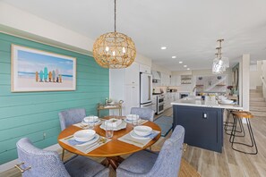 A modern kitchen with white cabinets, a central island, and bar stools. - Enchanting Ocean View Townhome | Walk to Beach, Dining & More (Encinitas)