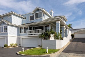 Ein zweistöckiges Haus mit Garage, einer überdachten Veranda und einem kleinen Garten.
