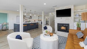 A modern living room with a fireplace, a dining area, and a kitchen. - Enchanting Ocean View Townhome | Walk to Beach, Dining & More (Encinitas)
