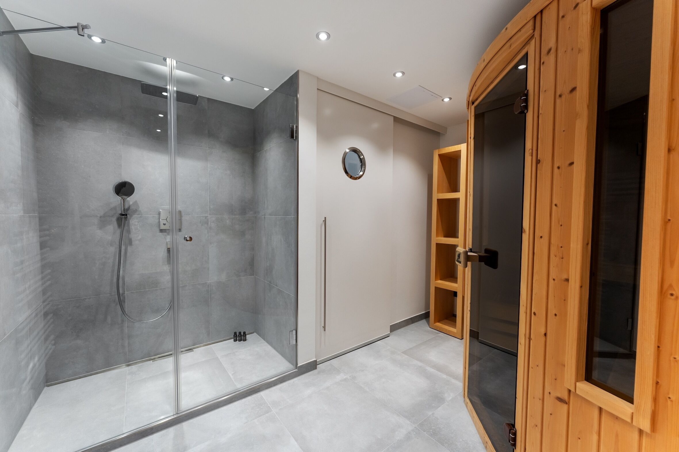 Un baño moderno con ducha de vidrio, un mueble de madera y un espejo en la pared.