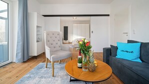 Una sala de estar moderna con un sofá, un sillón y una mesa de centro, con un jarrón de flores y una piña.