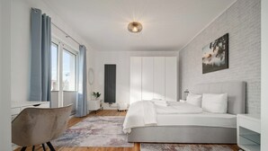 Un dormitorio moderno con una cama grande, un escritorio y una silla.