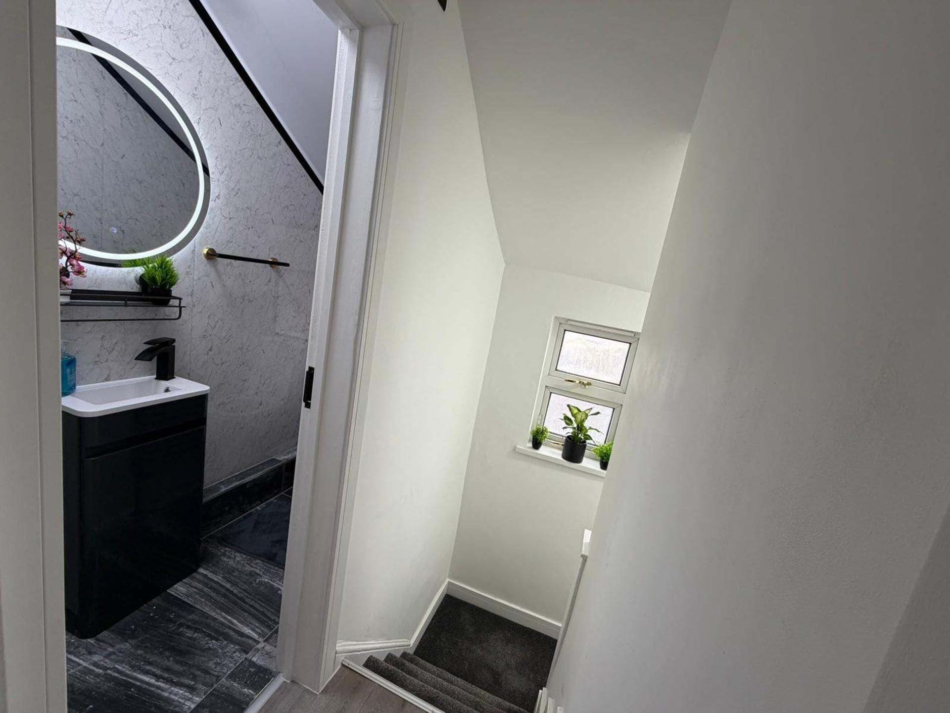 A modern bathroom with a curved mirror, a black sink, and a dark floor.