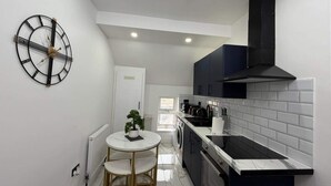 A modern kitchen with a round dining table, a built-in oven, and a black stove. - Cardiff Central Gem - 2 Bed Apartment (Cardiff)
