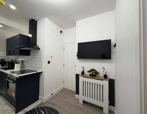 Une cuisine moderne avec une hotte noire, un dosseret de carrelage blanc et un plan de travail noir.