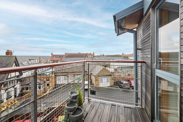 A balcony with a metal railing, a wooden floor, and a view of the surrounding neighborhood. - Host Stay The Shipshape (Seahouses)