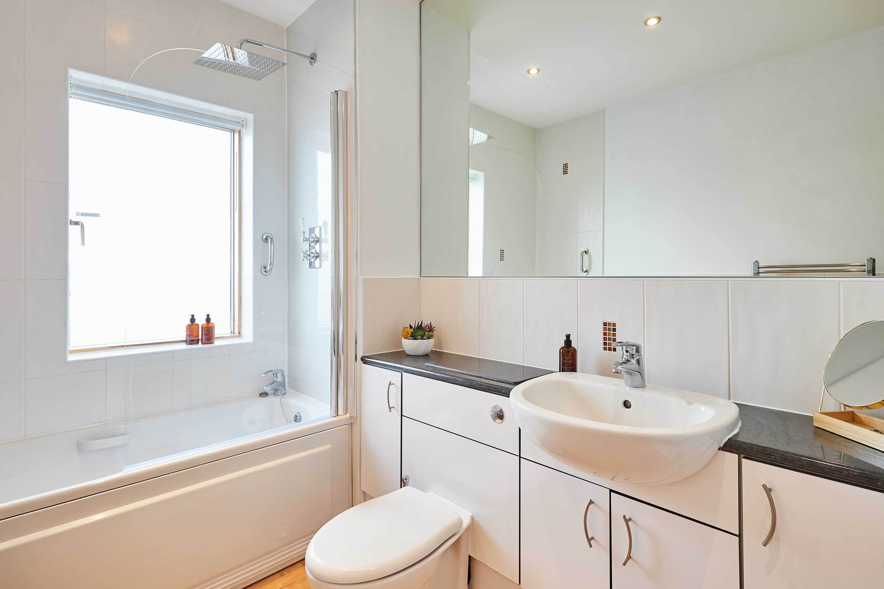 A modern bathroom with a bathtub, toilet, sink, and a large mirror.