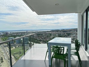 Ein Balkon mit Glasgeländer, einem Tisch und zwei Stühlen.