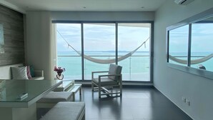 A modern room with a large window, a hammock, a chair, and a small table. - w Amazing 3BR w Ocean View in Marbella (Cartagena)