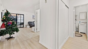 Ein modernes Wohnzimmer mit Weihnachtsbaum, grauem Sofa und Wand-Fernseher.