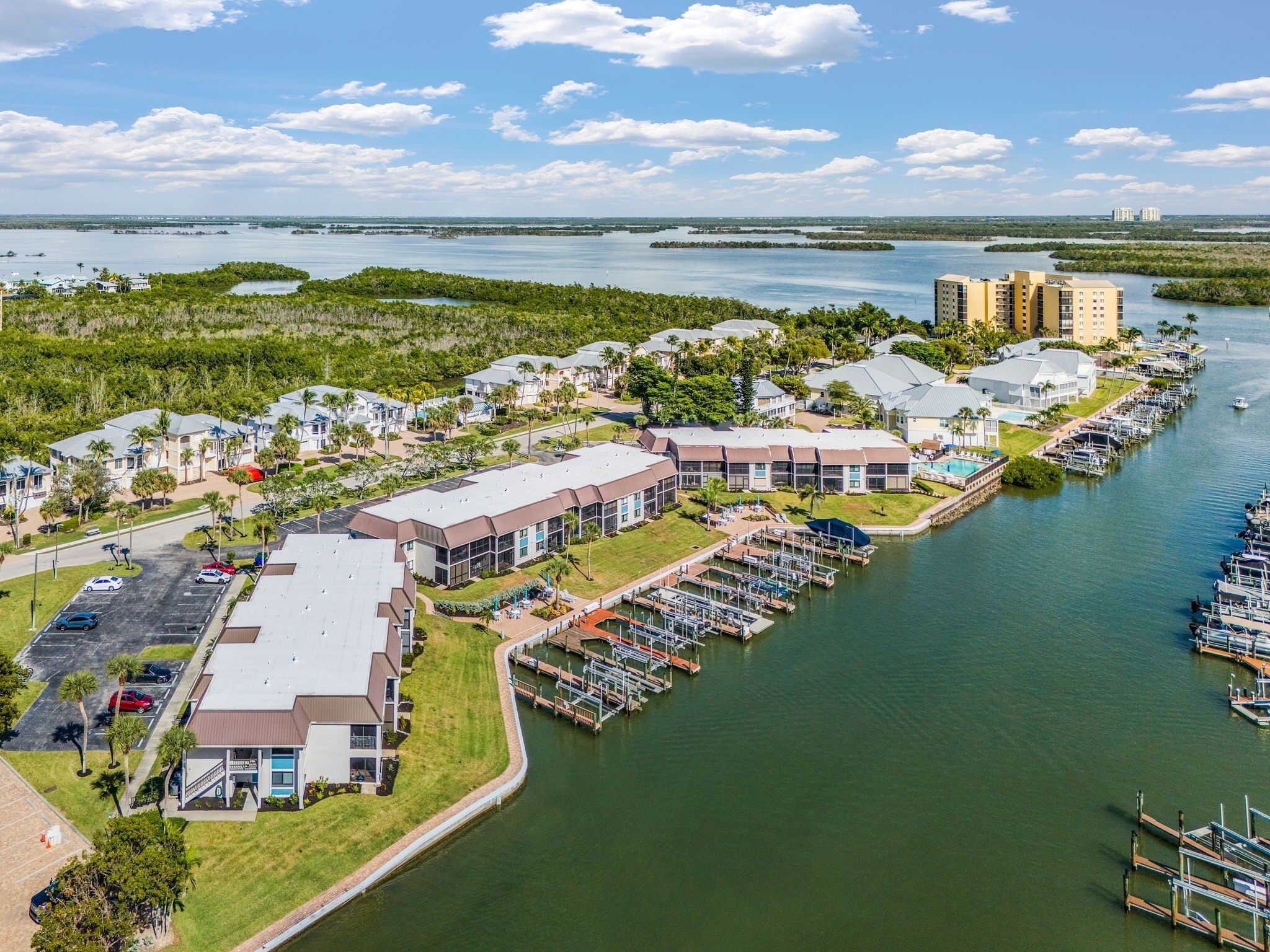 Vue aérienne d’une marina avec des bâtiments, un parking et des bateaux.