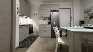 Eine moderne Küche mit weißen Schränken, einem Edelstahl-Kühlschrank und einem Essbereich mit Tisch und Stühlen.