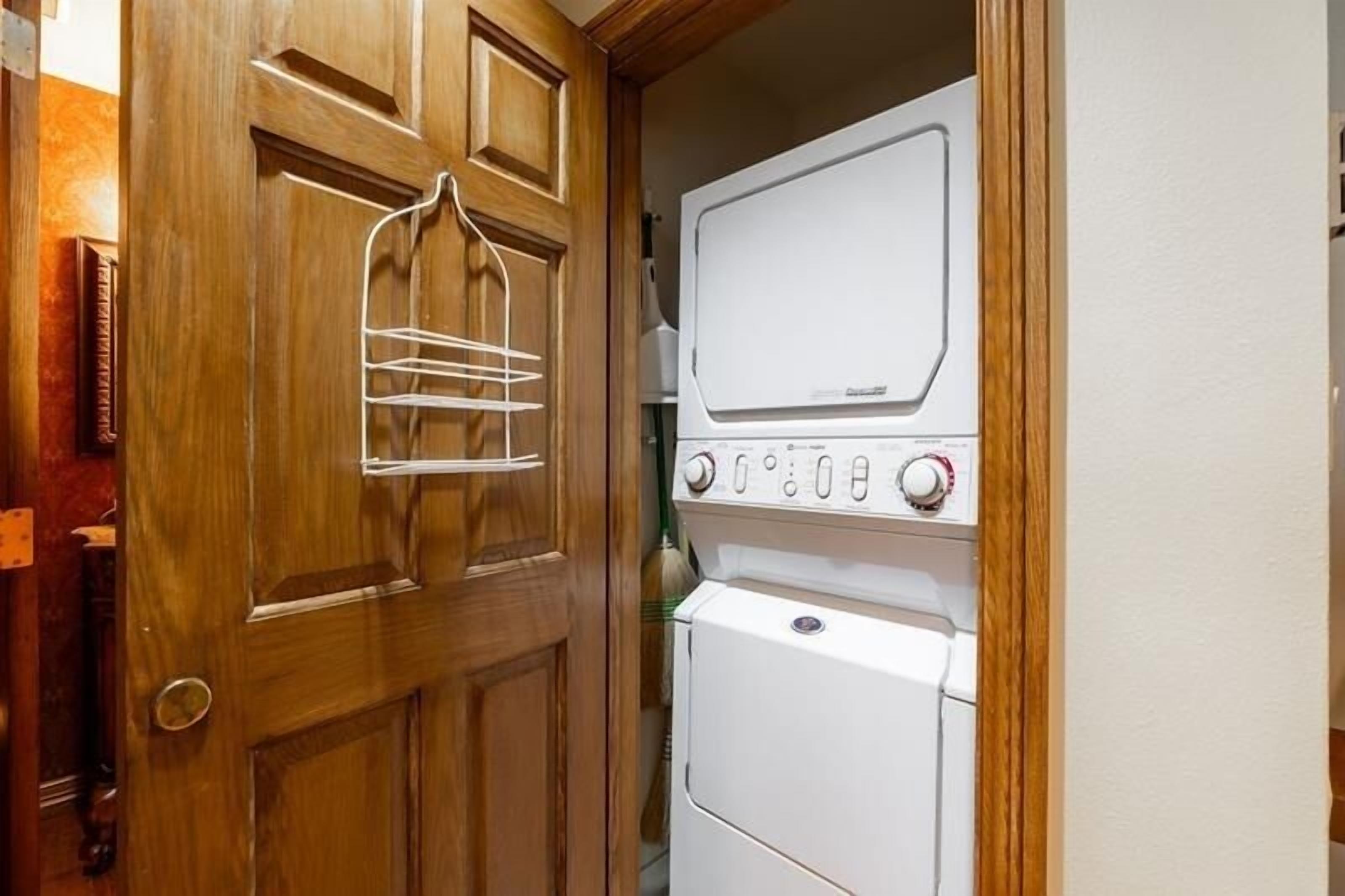 Une buanderie avec une porte en bois, un étendoir et des machines à laver empilées.