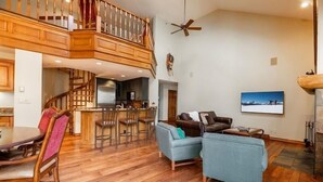 A spacious living area with a wooden staircase, a dining area with a round table, and a cozy seating arrangement. - Strawberry Park #604 5 Bedroom Condo (Avon)