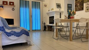 Ein modernes Wohnzimmer mit einer Couch, einem Esstisch mit Stühlen, einem Fernseher und einem Kamin.