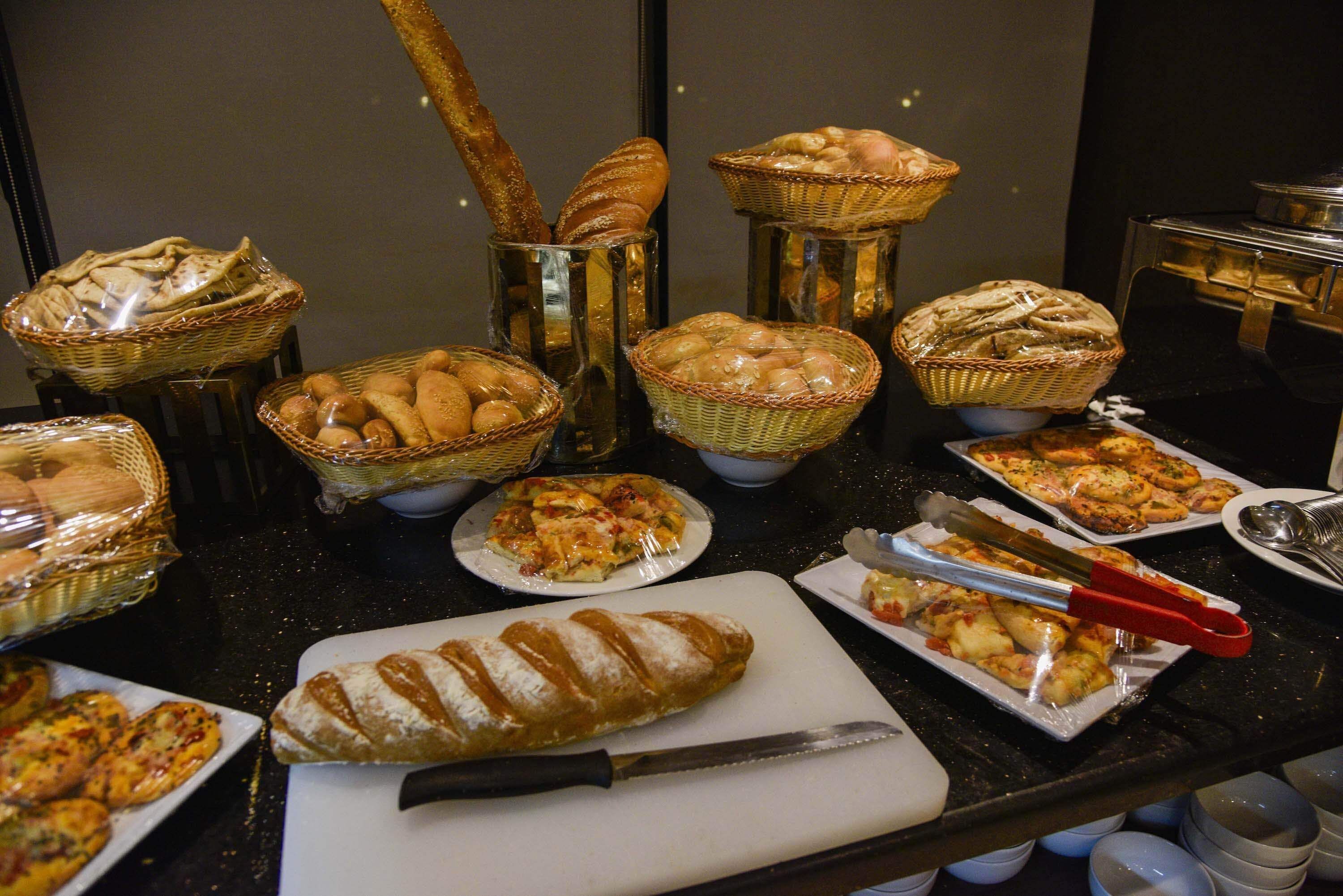 Un buffet con diversi pani, pasticcini e pizze.
