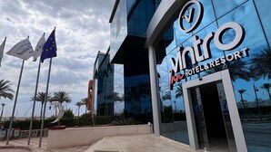 Un edificio moderno con fachada de vidrio y el letrero "Vintro Hotel & Resort".