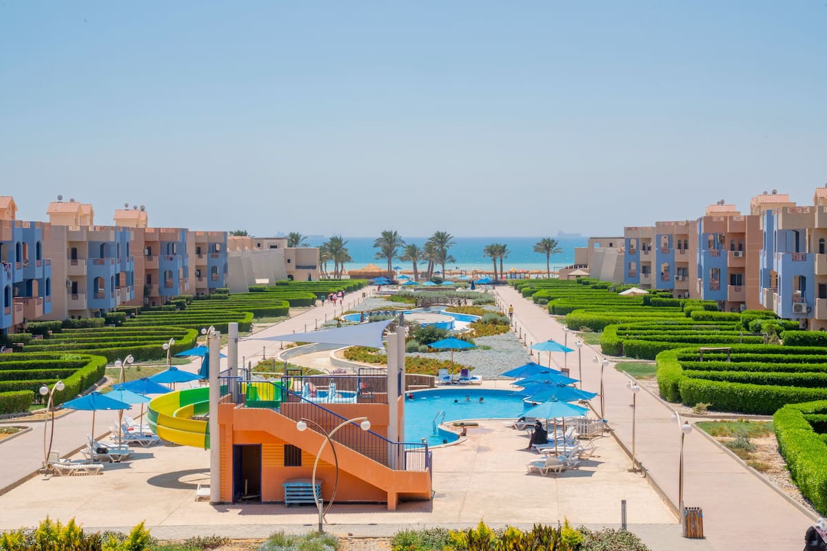 Un complexe hôtelier doté d’une piscine, de chaises longues et offrant une vue sur la mer.