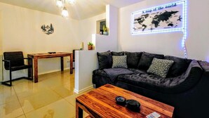 A living room with a sofa, a wooden coffee table, a dining table, and a wall-mounted map. - Apartment Liana with Castle View (Hechingen)