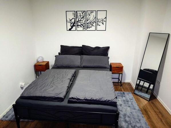 A bedroom with a bed, two nightstands, a mirror, and wall art.