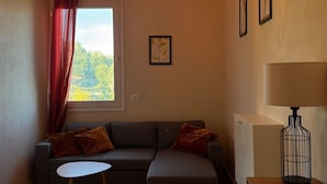 A cozy living room with a sofa, a small table, a lamp, and a window with curtains. - Bed@Breakfast, 2 double rooms, 1 apartment for 6-8 persons (Kryevidh)