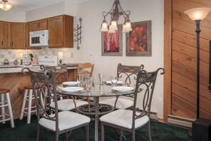 A kitchen with wooden cabinets, a white microwave, and a dining area with a glass table and metal chairs. - Sunsong 3F New split-level 3 bedroom in Fraser with private deck (Fraser)