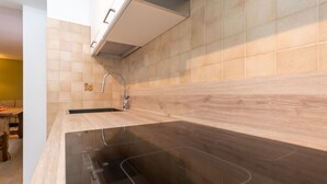 Uma cozinha moderna com bancada preta, painel de madeira e torneira de aço inoxidável.