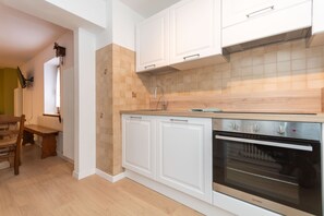 A kitchen with white cabinets, a wooden countertop, a built-in oven, and a window with a view. - Elvira's House-First Floor (Alleghe)
