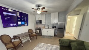 Un espacio habitable compacto con comedor, kitchenette y un sofá verde.