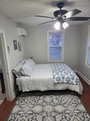 A bedroom with a bed, a ceiling fan, a window with blinds, and a patterned rug. - Cozy 1-bedroom building in terrific Springfield with AC (Springfield)
