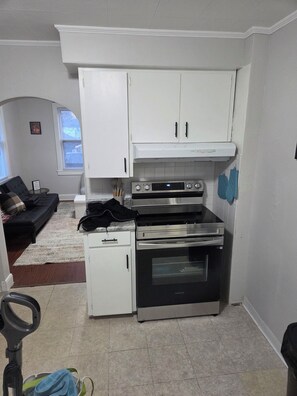 A compact kitchen with white cabinets, a built-in oven, and a microwave. - Cozy 1-bedroom building in terrific Springfield with AC (Springfield)
