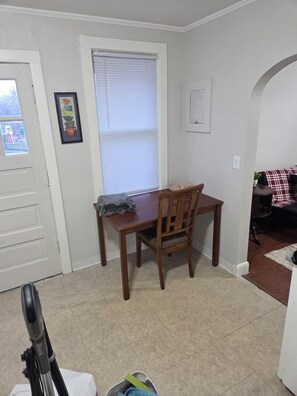 A dining area with a wooden table and chairs, a window with blinds, a framed picture on the wall, and a door leading outside. - Cozy 1-bedroom building in terrific Springfield with AC (Springfield)